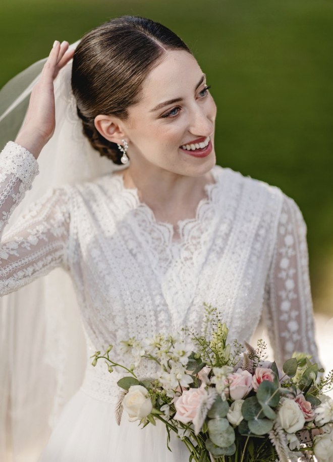 Bridal makeup and white lace wedding gown with floral bouquet